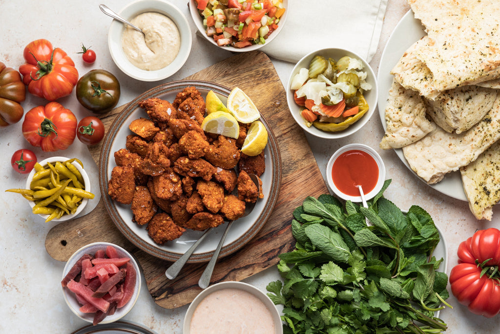 A table flatlay with Claire Thomson's tomato falafels, flatbreads, chopped salad and pickles. 