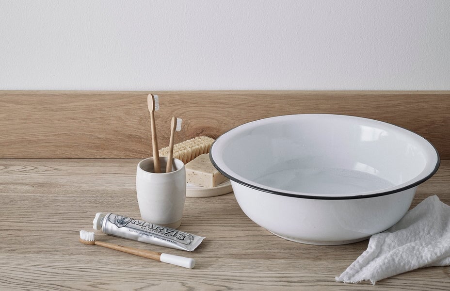 Minimal bathroom comprising toothbrushes, toothbrush holder, basin, flannel, toothpaste, soap and nailbrush