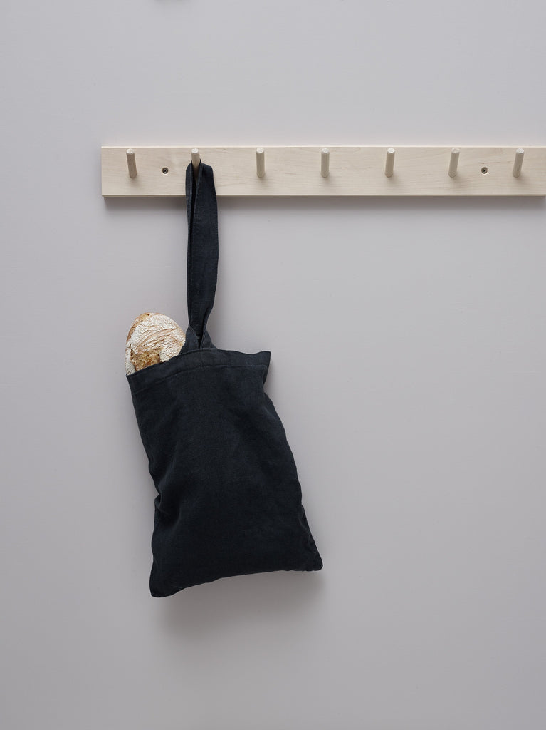 Linen charcoal bread bag hanging from hooks holding loaf of bread
