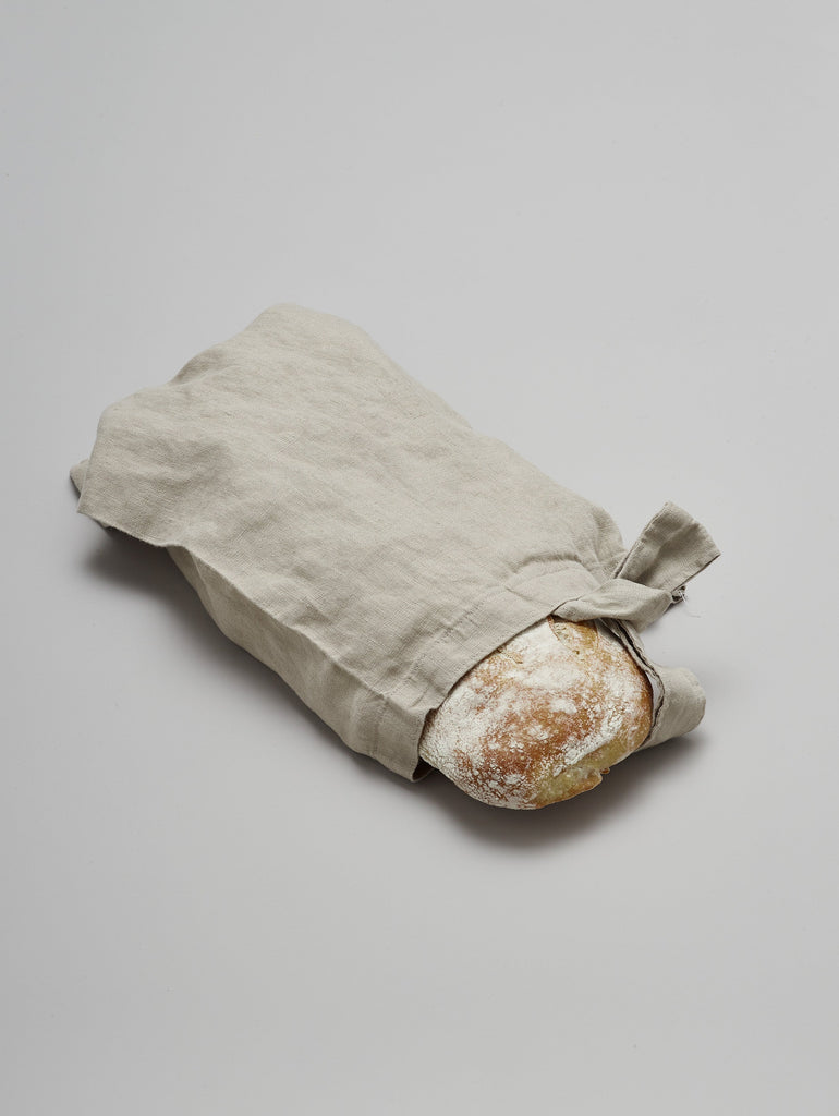 Handmade natural linen bread bag holding a loaf of bread